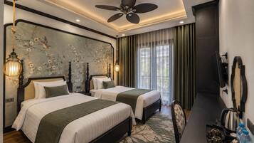 A hotel room with two beds, a ceiling fan, a wall-mounted TV, and a window with curtains.