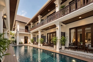 A hotel with a swimming pool, outdoor seating, and multiple balconies.