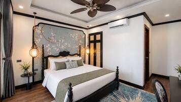 Un dormitorio con una cama grande, un ventilador de techo, un equipo de aire acondicionado y un adorno de pared.