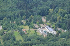 Surrounded by dense forest, this rural property features a main building with a sloped roof, set amidst a working farm or estate.