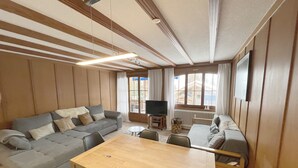 A modern living room with a sofa, a dining table, and a TV. - "Petit flocon" Apartment in the center of Verbier (Val de Bagnes)