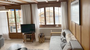 A living room with a television, sofa, and wooden walls. - "Petit flocon" Apartment in the center of Verbier (Val de Bagnes)