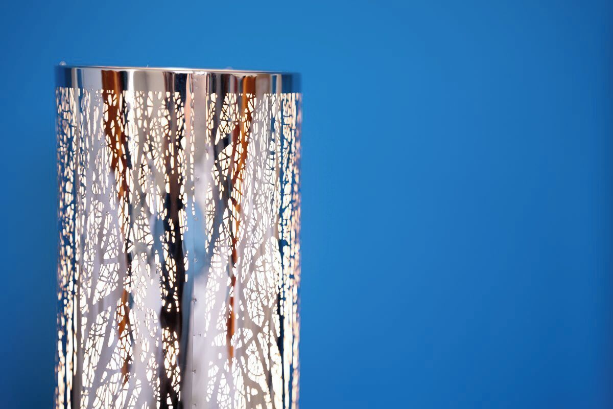 A cylindrical structure with a reflective surface and intricate white patterns.