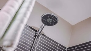 Un pommeau de douche au design circulaire, doté de plusieurs jets, fixé sur un mur orné de motifs de carreaux.