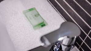 Une serviette blanche avec une étiquette verte, posée sur le lavabo d’une salle de bain.