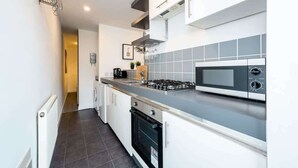 Cocina moderna con estufa a gas, microondas y horno empotrado.