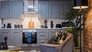 Una cocina moderna con armarios grises, horno empotrado y una mesa redonda de vidrio.