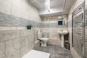 A modern bathroom with a toilet, sink, and shower area.