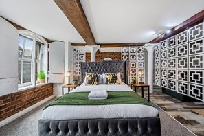 A bedroom with a large bed, a brick wall, and a patterned wall unit. - Host & Stay | Mathew Street Studio (Liverpool)