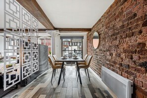 A dining area with a brick wall, a decorative white partition, and a view through a window.