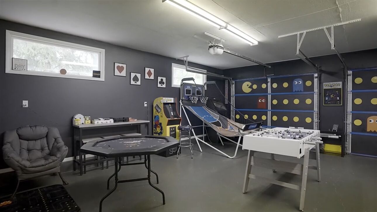 A room with a foosball table, a trampoline, and a basketball hoop.