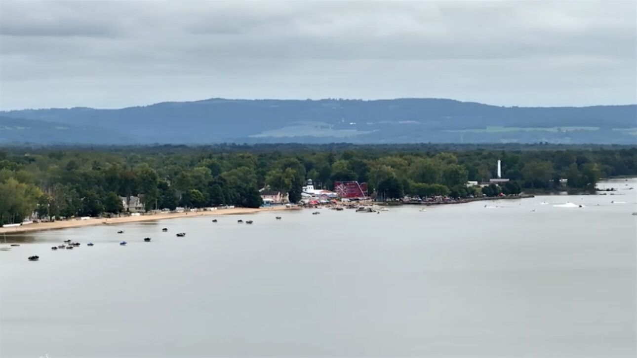 A coastal town with a lighthouse, boats, and a red structure near the shore.
