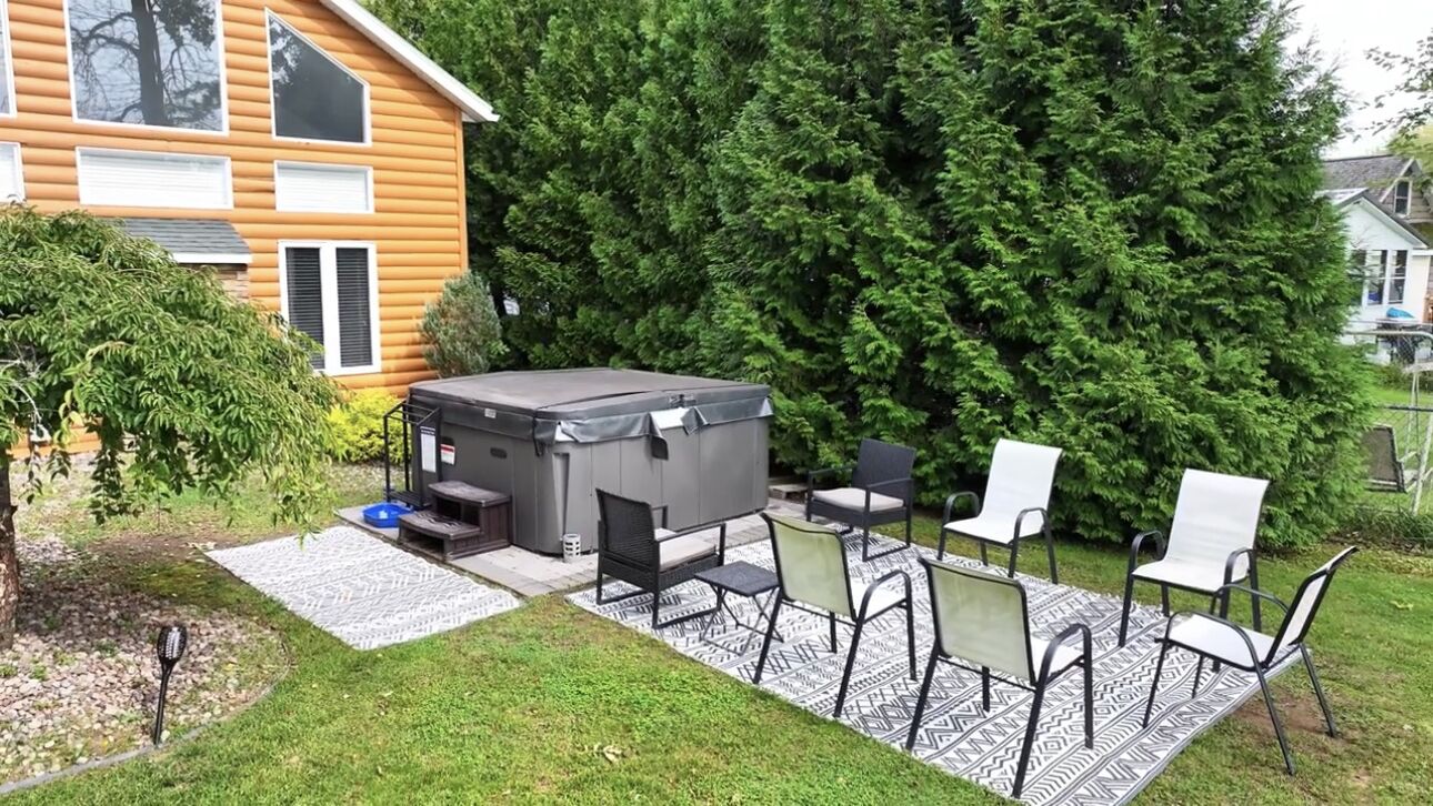 Un giardino con idromassaggio, posti a sedere all'aperto e una casa in legno.