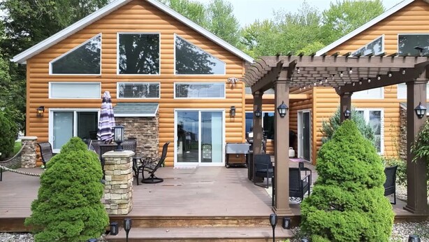 A log cabin with a deck, outdoor seating, and a pergola.