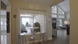 A cozy living room with a fireplace, a dining area with a table and chairs, and a view of the outdoors.