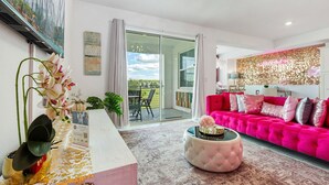Ein modernes Wohnzimmer mit heller Farbgestaltung, einem großen Fenster und Blick ins Freie.