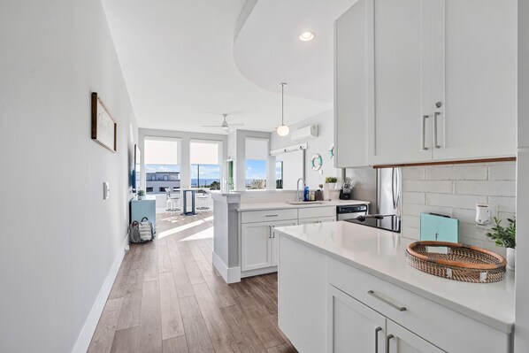 Una cocina moderna con armarios blancos, una isla central y vistas al exterior.