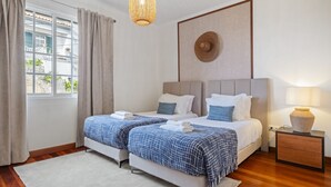 A double bed room with a view of the outside, a bedside table with a lamp, and a wall-mounted artwork. - Sunny House by Homie (Ponta do Sol)
