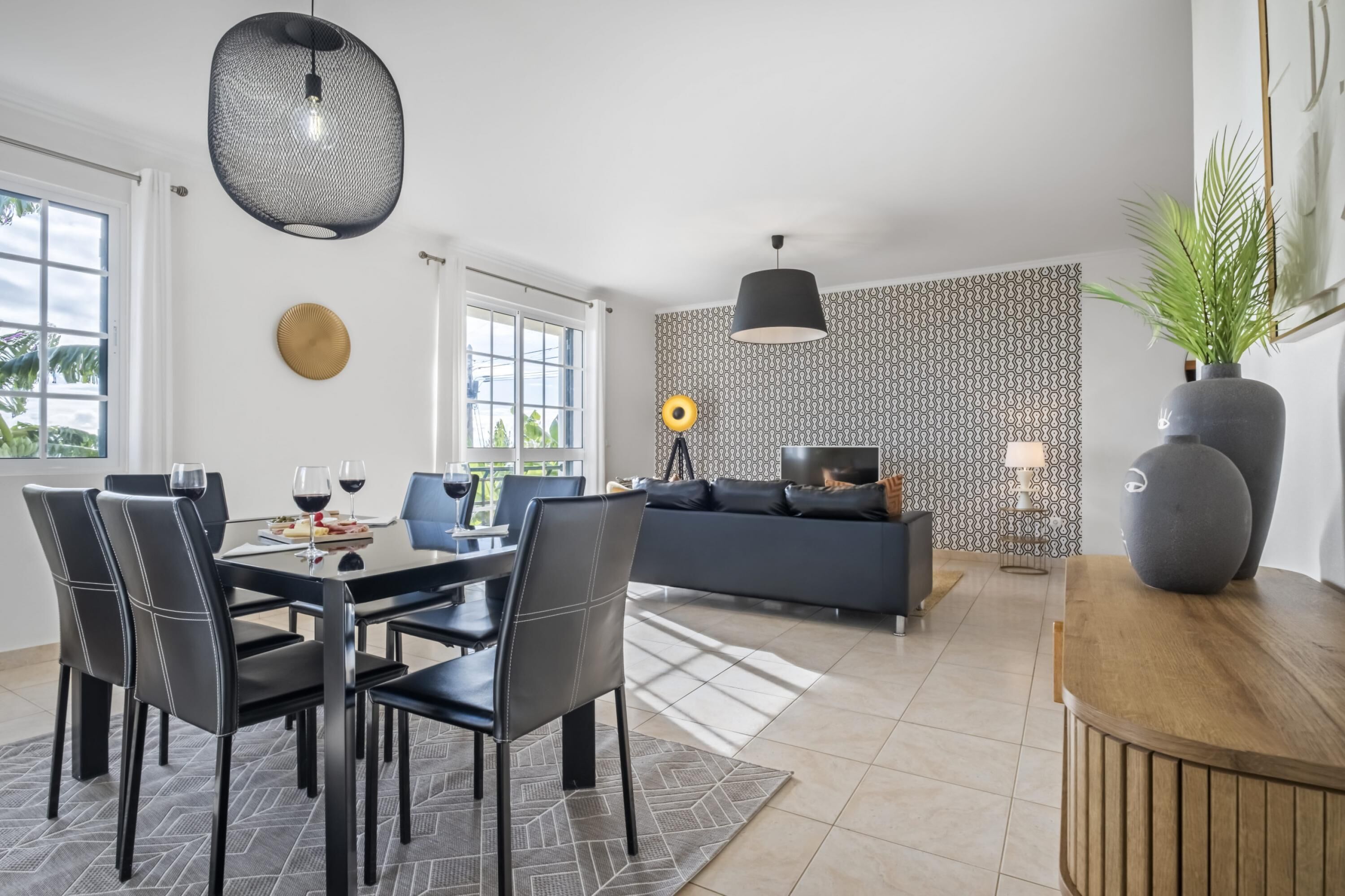 A modern living room with a dining area, featuring a sofa, a coffee table, and a dining table with chairs.