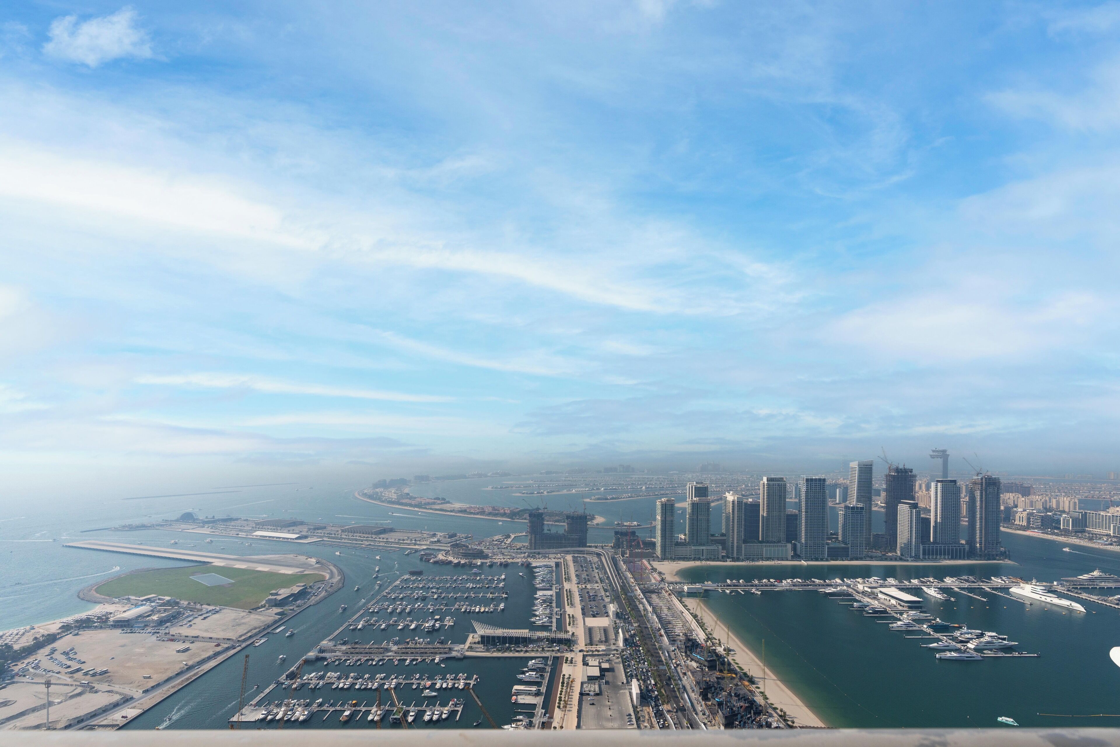 Vista aèria d'una ciutat costanera amb un port esportiu, edificis alts i cel serè.