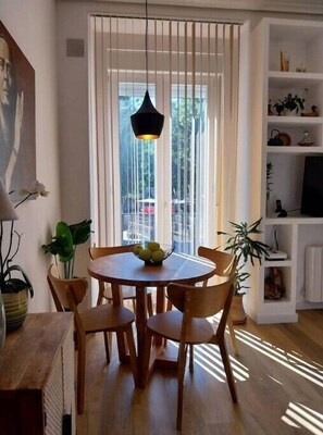 Enjoy meals in this cozy dining area with a round table and six chairs, featuring a pendant light and large window with vertical blinds.