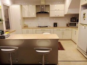 Eine moderne Küche mit weißen Schränken, einer zentralen Kochinsel mit Barhocker, einer Mikrowelle und einem Einbauofen.