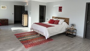 A bedroom with a bed, a nightstand, a wooden wardrobe, a red rug, and a poster on the wall.