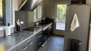 A modern kitchen with a stainless steel range hood, a built-in dishwasher, and a refrigerator.