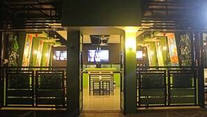 Vestíbulo de hotel con recepción, zona de estar y una pantalla de televisión.