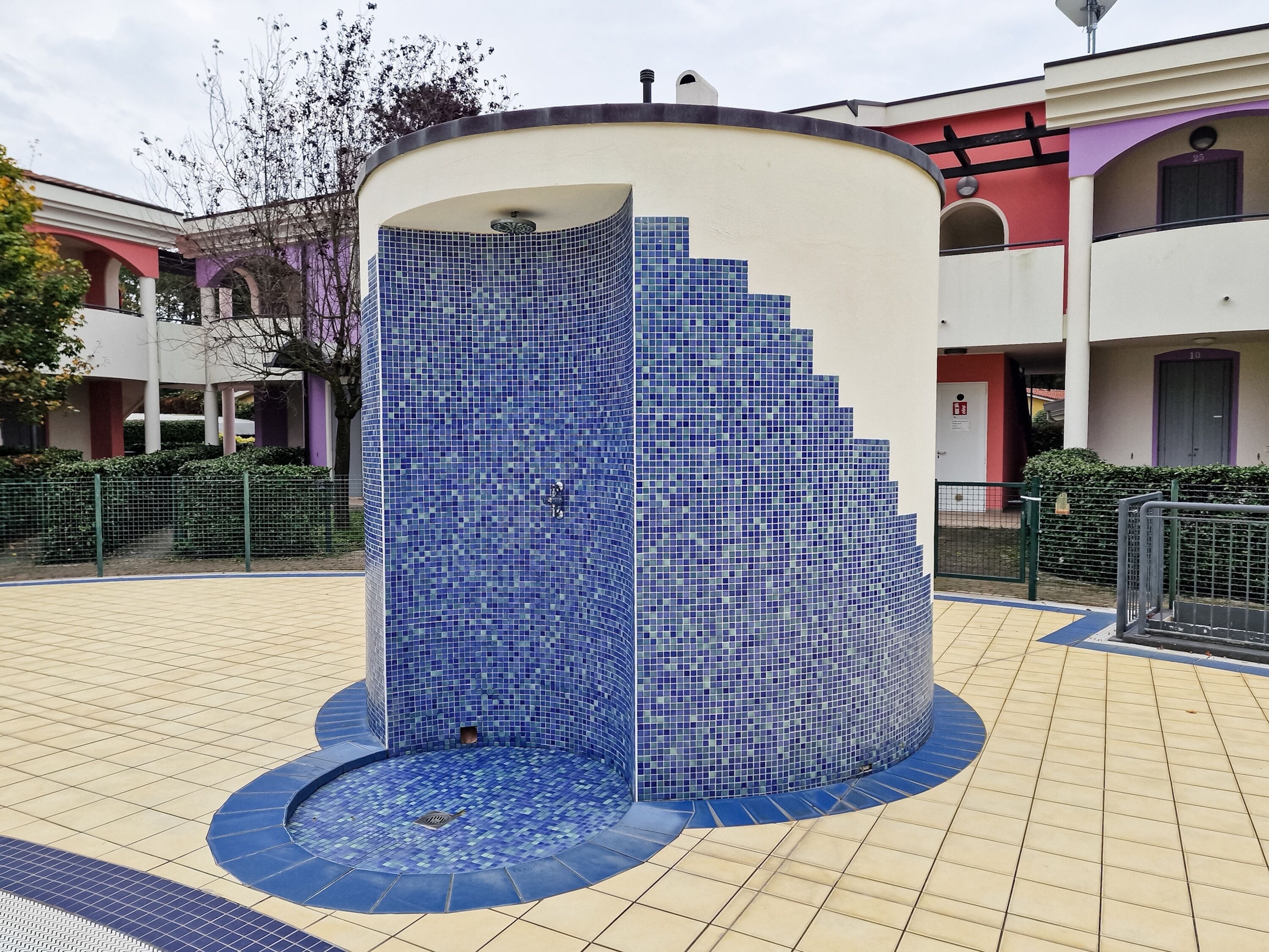 A circular water feature with a mosaic tile design, surrounded by a tiled walkway.