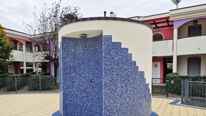 A circular water feature with a mosaic tile design, surrounded by a tiled walkway. - Holiday Village Apartment With Pool and Garden (San Michele al Tagliamento)