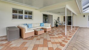 A covered outdoor patio with a sectional sofa, a small table, and a trash bin. - Pet-friendly Cape Coral Gem w/ Pool, 3 Mi to Beach (Cape Coral)