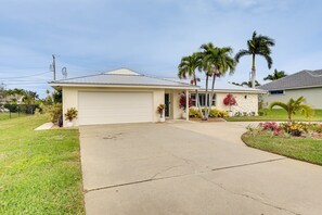 A single-story house with a garage, a driveway, and a well-maintained lawn. - Pet-friendly Cape Coral Gem w/ Pool, 3 Mi to Beach (Cape Coral)