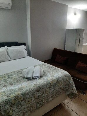 A hotel room with a bed, a sofa, and a wardrobe.