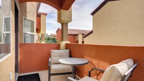 A balcony with a round table and two chairs, beige cushions, and a red-tiled roof. - Resort Pool & Spa Access: Mesquite Condo! (Mesquite)