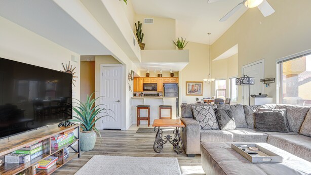 A spacious living area with a large flat-screen TV, a sofa, a coffee table, and a bookshelf filled with board games. - Resort Pool & Spa Access: Mesquite Condo! (Mesquite)