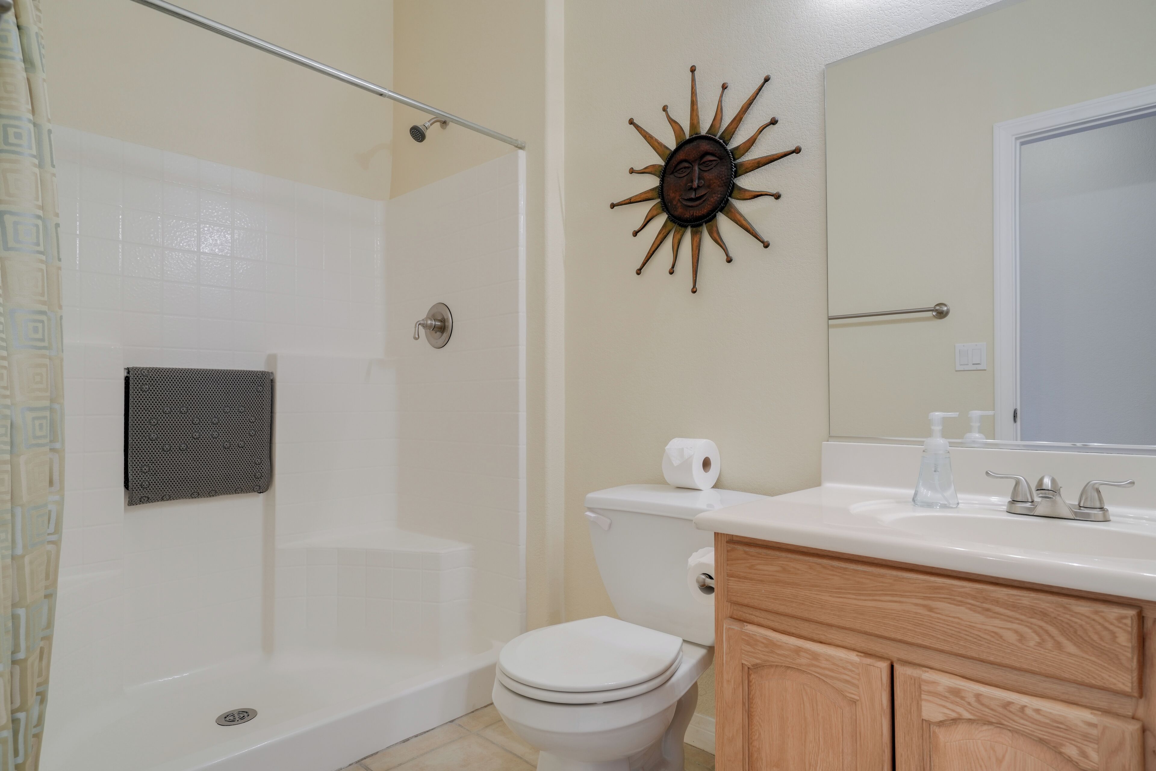 A bathroom with a shower, toilet, and vanity with a mirror.