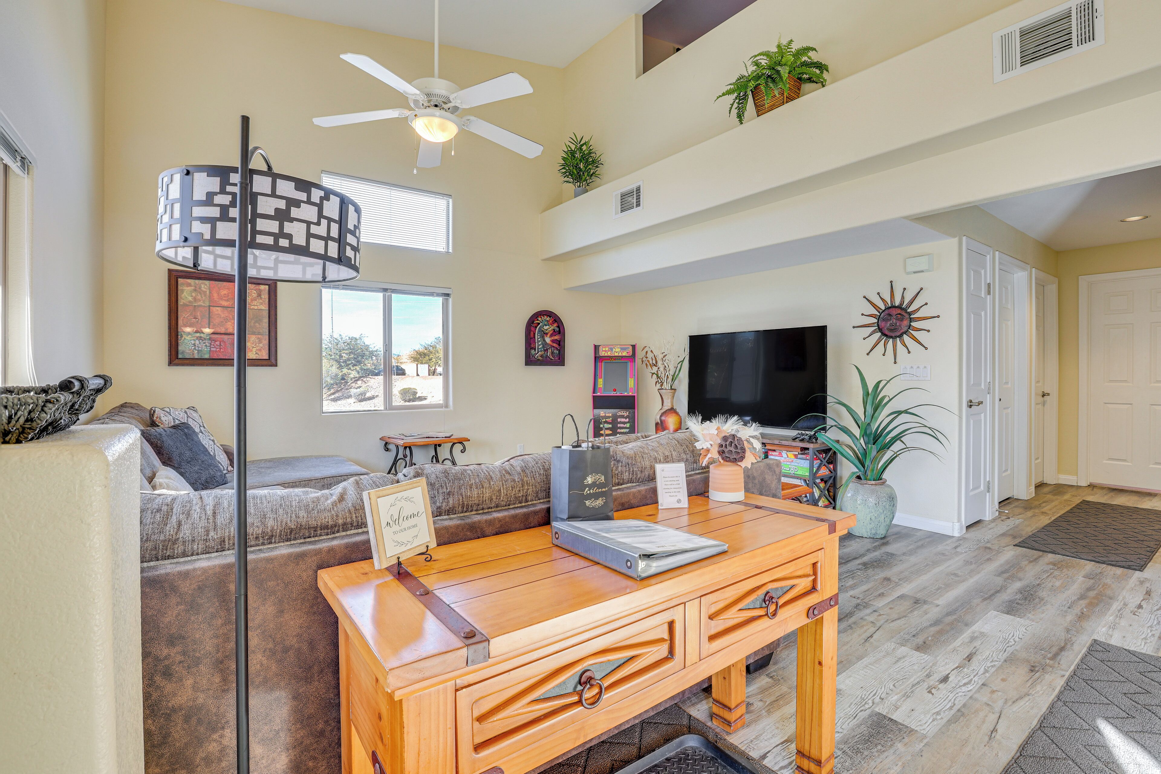 A spacious living room with a ceiling fan, a sofa, a coffee table, and a television.