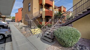 A multi-story building with a central staircase, a covered parking area, and a small landscaped area with a bush. - Resort Pool & Spa Access: Mesquite Condo! (Mesquite)