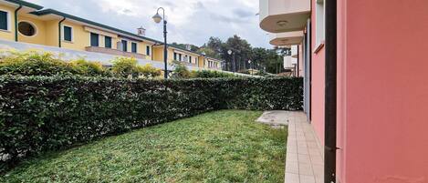 A residential building with a well-maintained lawn, a hedge, and a tiled pathway.