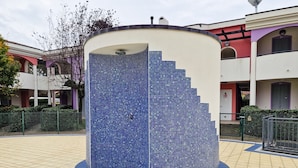 Una vasca d'acqua circolare con decorazioni in mosaico, circondata da un percorso piastrellato.