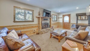 Una sala de estar acogedora con sofás de cuero, una chimenea y ventanas amplias.