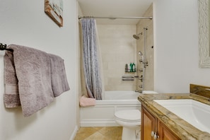 A bathroom with a bathtub, toilet, and a vanity with a sink.