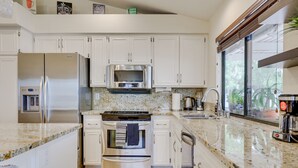 A modern kitchen with white cabinets, stainless steel appliances, granite countertops, and a large window providing natural light. - Serene Poway Home w/ Private Pool: Pet Friendly! (Poway)