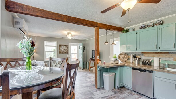 A kitchen with teal cabinets, a dishwasher, and a dining area with a glass table and chairs. - Lovely Smoky Mountain Cottage w/ Deck + Views! (Topton)