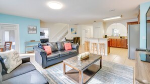 A modern living room with a dark leather sofa, a coffee table, and a kitchen area in the background. - ~ 6 Mi to Disney: Kissimmee Vacation Villa w/ Pool (Kissimmee)