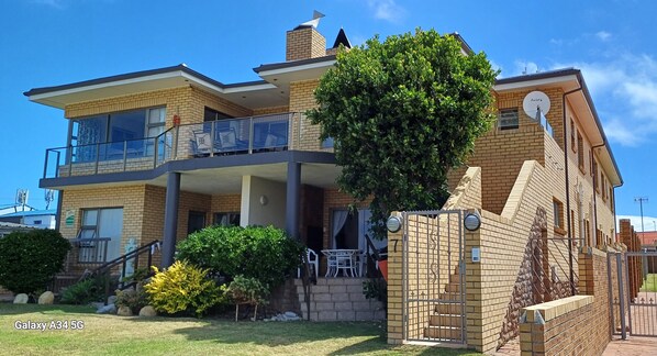 A two-story house with a balcony, a brick exterior, and a small garden. - Kleinmond Panorama Holidays (Kleinmond)