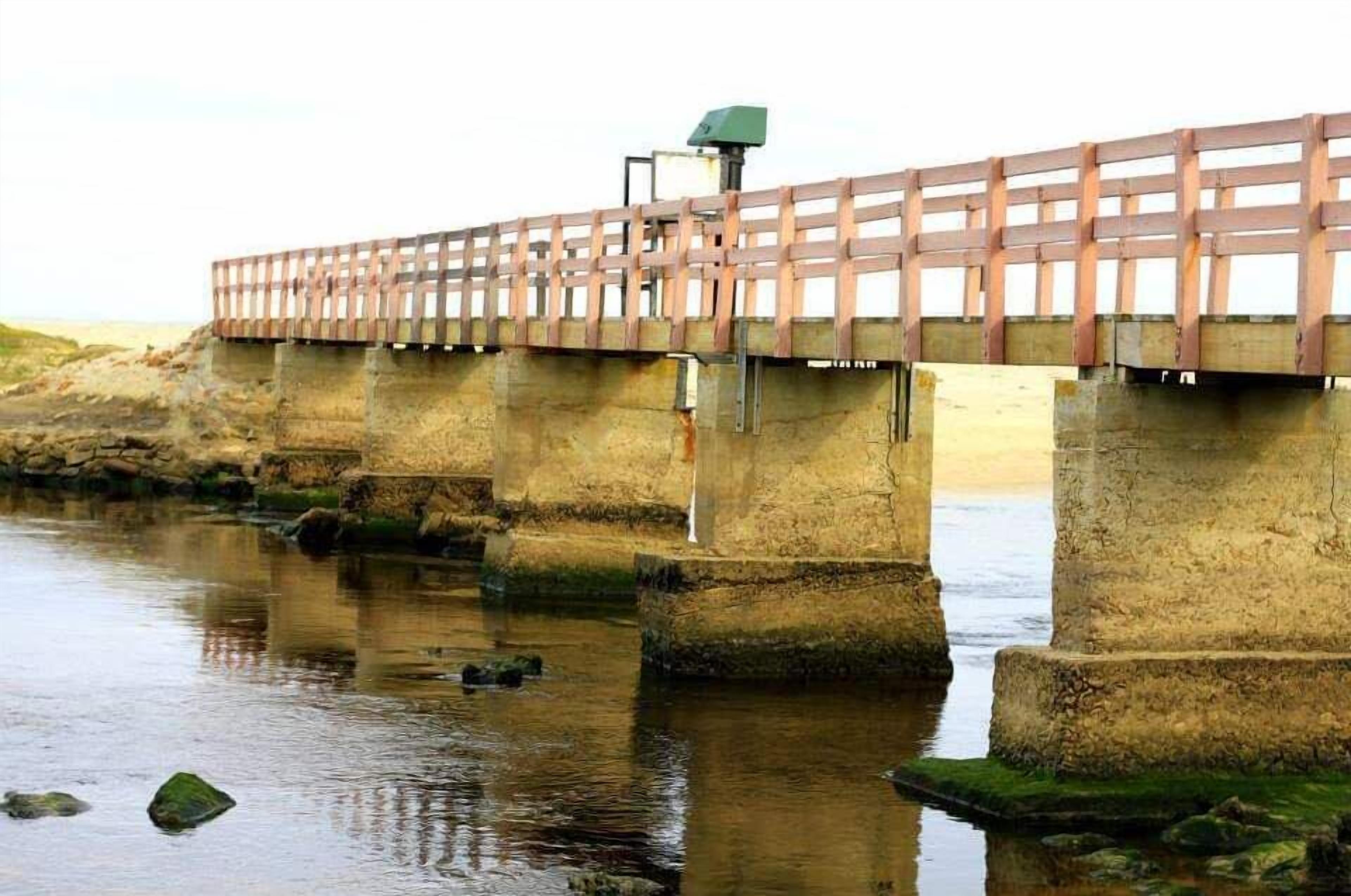 A concrete bridge with a wooden walkway over a body of water.