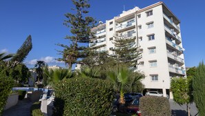 A multi-story residential building with balconies, a swimming pool, and surrounding greenery. - Palm Beach Sea View Apt by TrulyCyprus (Limassol)