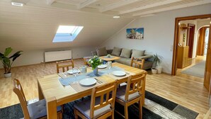 A dining area with a wooden table and chairs, a black and white rug, and a skylight.